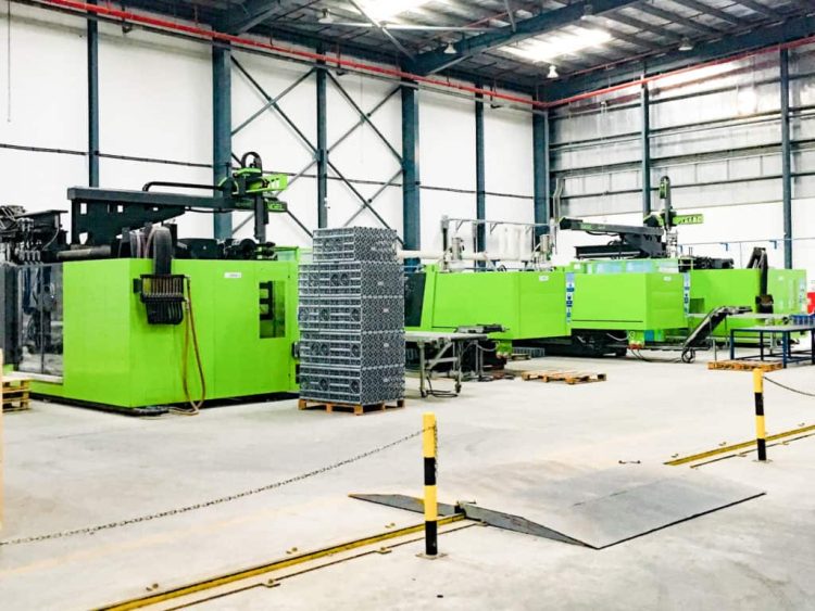 Wide interior view of a clean, organized industrial machinery storage facility with equipment properly covered and spaced for airflow