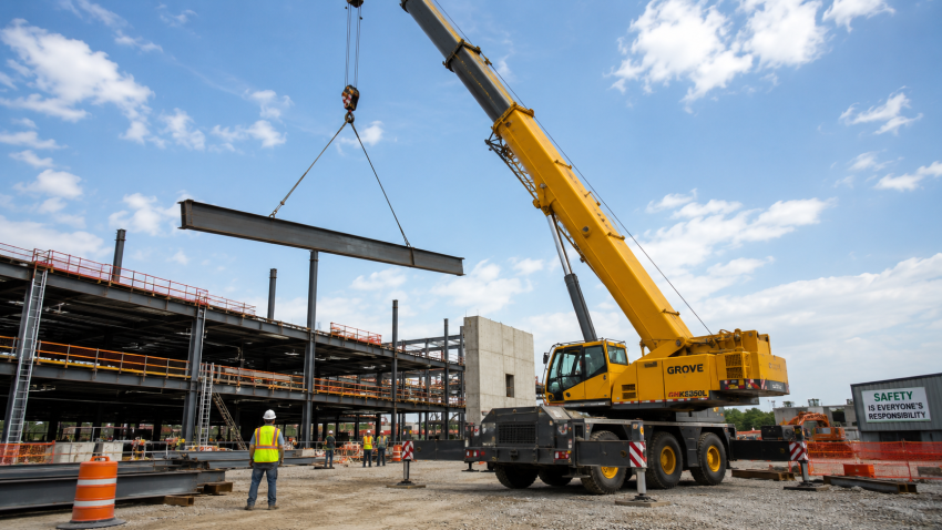 Mobile crane lifting a steel beam on an active construction site